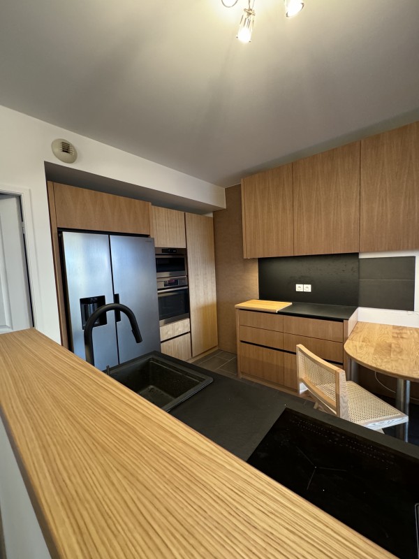 Cuisine en bois sur mesure avec plan de travail noir dans un appartement